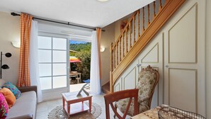 Une pièce comprenant un canapé, une table à manger, une chaise, un escalier et une vue sur l’extérieur, visible à travers une porte vitrée.