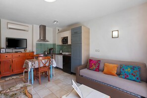 A compact living space with a kitchenette, a sofa with colorful cushions, a dining table with chairs, and a television. - Lavender Cottage, residence with pool (Callian)