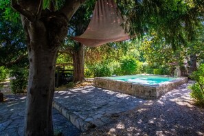 Une piscine en pierre, entourée d’arbres, et un hamac suspendu.