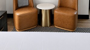 Una habitación con dos sillones de cuero, una mesita redonda y un cuadro abstracto enmarcado en la pared.