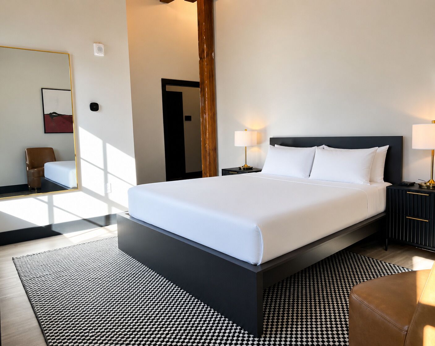 Ein modernes Hotelzimmer mit einem großen Bett, Nachttischen, einem Spiegel, einem Sessel und einem gemusterten Teppich.