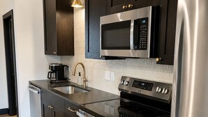 Una cocina moderna con armarios de madera oscura, electrodomésticos de acero inoxidable y piso de madera.