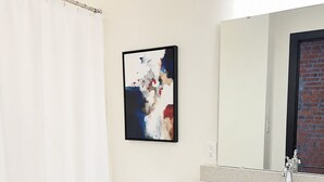 Un baño moderno con inodoro blanco, tocador negro, lavamanos blanco y cortina de ducha.