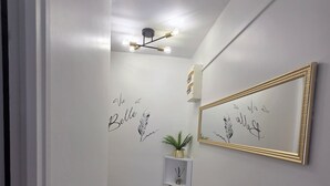 Een hal met een streeptjesvloer, een spiegel aan de muur en decoratieve wandkunst.