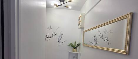 A hallway with a speckled floor, a wall-mounted mirror, and decorative wall art.
