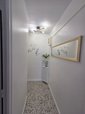 Ein Flur mit einem gemusterten Boden, einem Wandspiegel und dekorativen Wandbildern.