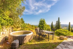 Un jacuzzi, una mesa de comedor y sillas en un jardín con vistas a las colinas.