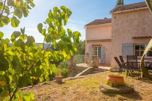 Una casa con escaleras de piedra, un patio con sillas y vistas del paisaje circundante.