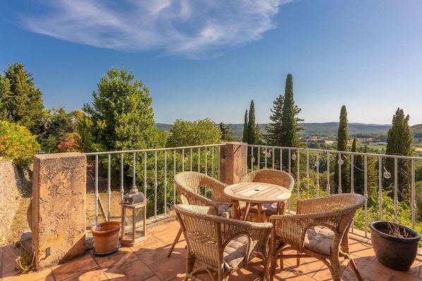 A terrace with wicker furniture, a table, and a potted plant. - Villa Andéria – Your Provençal Retreat in Callian (Callian)