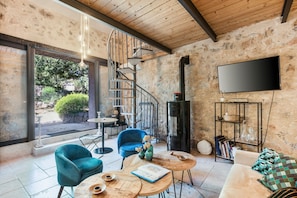 A modern interior with a spiral staircase, a flat-screen TV, and a cozy seating area with a sofa and chairs.