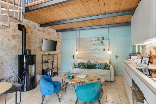 Een gezellige zithoek met een bank, blauwe stoelen, een salontafel, een televisie en een open haard.