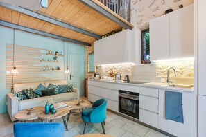 Une cuisine moderne avec des meubles blancs, un pare-feu en pierre et un four encastré.