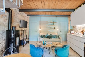 Un espacio habitable moderno con chimenea, un sofá, una mesa de centro y sillas azules.