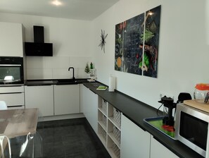 Eine moderne Küche mit weißen Schränken, einer schwarzen Arbeitsplatte und einer Mikrowelle.