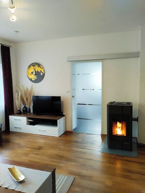 A living room with a television, a fireplace, and a decorative globe on the wall. - Arrive, take a deep breath and enjoy Private bungalow for your private time-out (Glashütten)