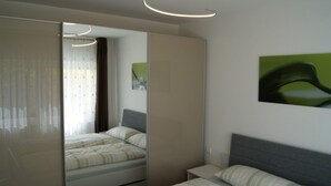 Una camera da letto con un letto, un comodino, uno specchio e un quadro appeso al muro.