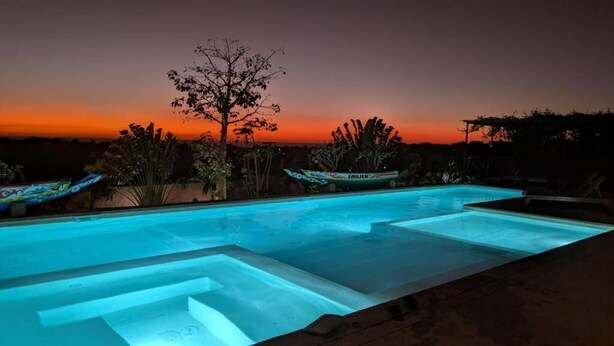 A swimming pool with a sunset view, surrounded by plants and a boat. - Lodge Terre et Mer (Guereo)