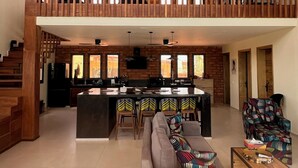 A spacious living area with a high ceiling, a kitchen with a central island, and a balcony with wooden railings. - Lodge Terre et Mer (Guereo)