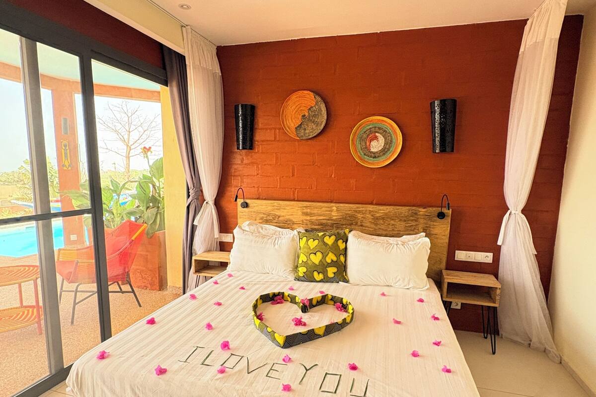 A bedroom with a bed, a ceiling fan, a view of the outdoors, and a decorative wall.