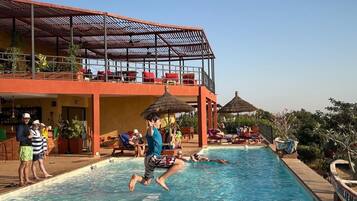 Una piscina al aire libre, sombrillas, sillones reclinables de piscina