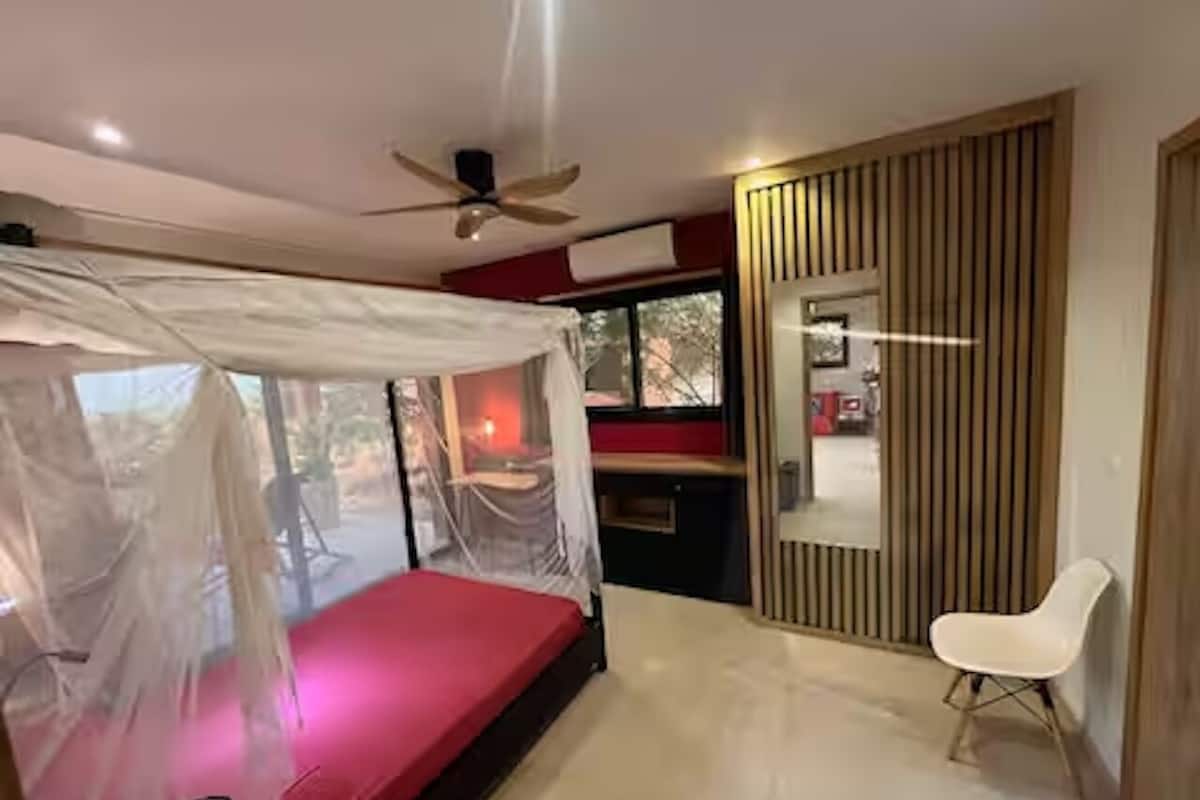 A bedroom with a bed, a ceiling fan, a bedside table, a chair, and a wardrobe.