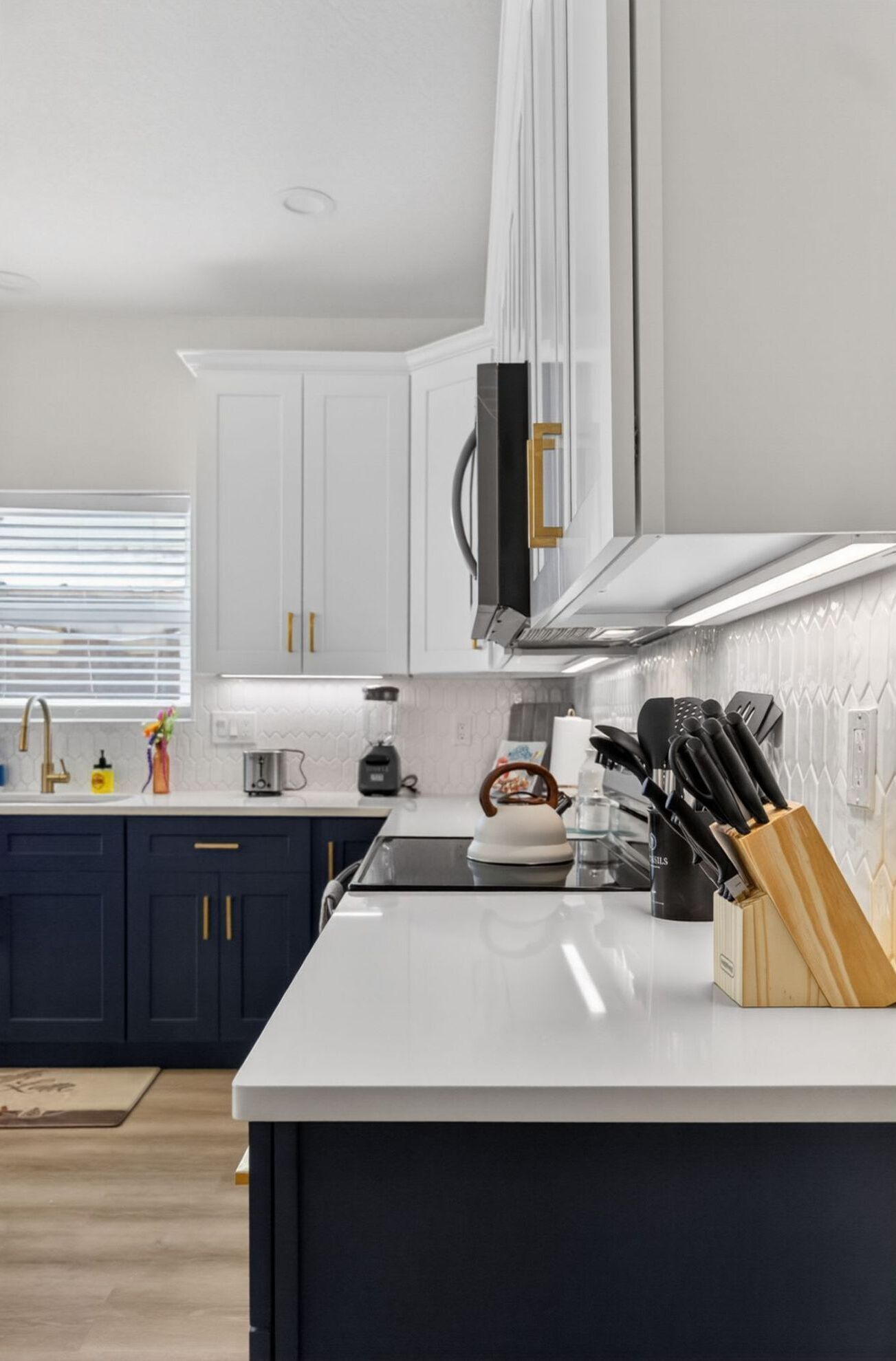 Una cocina moderna con armarios blancos, una encimera negra y un hervidor.