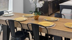 A modern kitchen with a wooden dining table, black chairs, and a hanging light fixture with multiple bulbs. - Lovely and Stylish Modern Home Near Downtown (San Antonio)