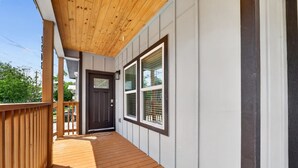 A wooden deck leading to a dark door with a window, white siding, and a wooden ceiling. - Lovely and Stylish Modern Home Near Downtown (San Antonio)