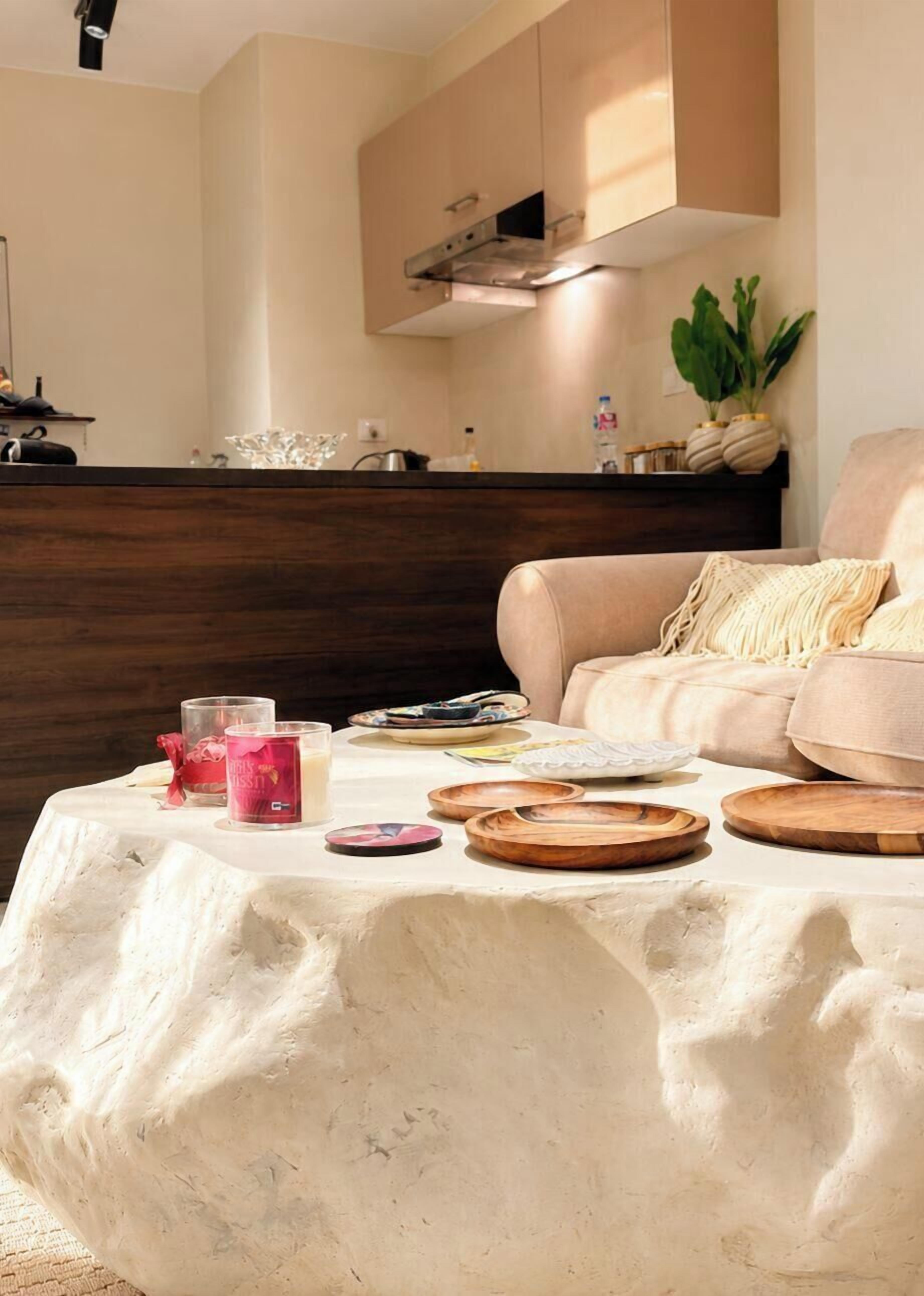Un salon chaleureux avec une table ronde, un canapé et, au fond, un coin cuisine.