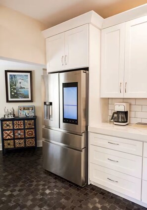 A kitchen with a stainless steel refrigerator, white cabinets, a coffee maker, and a decorative tile cabinet. - McDonald Manor/Walk To DT Mt Dora/Boat Parking (Mount Dora)