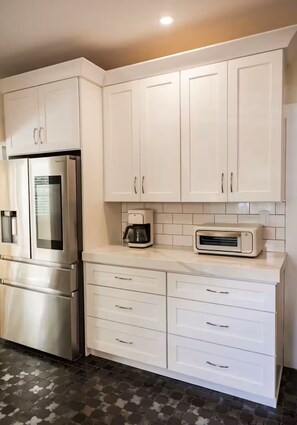 A modern kitchen with white cabinetry, stainless steel appliances, and a tiled backsplash. - McDonald Manor/Walk To DT Mt Dora/Boat Parking (Mount Dora)