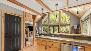 Una cocina con armarios de madera, una puerta negra y encimera de piedra.