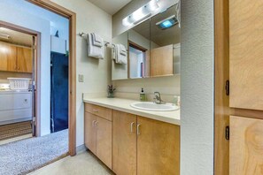 A bathroom with wooden cabinets, a sink, a mirror, and a towel rack. - Two Separate Units at this Incredible Riverfront Oasis with Wraparound Deck (Florence)