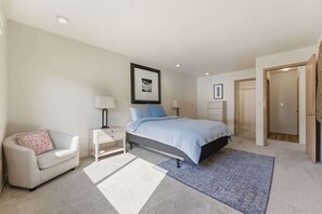 A bedroom with a bed, a bedside table, a chair, a rug, and a door. - Two Separate Units at this Incredible Riverfront Oasis with Wraparound Deck (Florence)