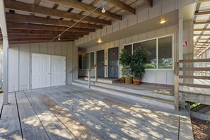 A covered outdoor area with wooden flooring, a staircase, and a door leading to a building. - Two Separate Units at this Incredible Riverfront Oasis with Wraparound Deck (Florence)