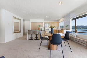 A modern kitchen with a dining area, large windows, and a view of the outdoors. - Two Separate Units at this Incredible Riverfront Oasis with Wraparound Deck (Florence)