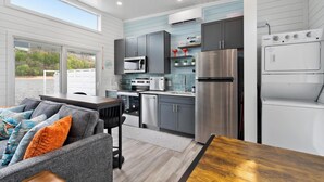 A modern kitchen with grey cabinets, stainless steel appliances, and a dining area with a grey sofa and wooden table. - Floatopia - A Unique Floating Retreat (Russell Springs)