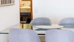 Un comedor moderno con una mesa de vidrio y sillas tapizadas en gris.