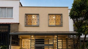 A modern building with two windows, a covered entrance, and a metal fence. - Nido del Bosque · Coffee Farm Host · Hot Springs 25 min · Pet Friendly (Dosquebradas)