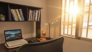 A workspace with a laptop, books, a desk lamp, and a window with sunlight. - Nido del Bosque · Coffee Farm Host · Hot Springs 25 min · Pet Friendly (Dosquebradas)
