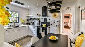 Una cocina moderna con armarios blancos, encimera negra y un original salpicadero hexagonal.