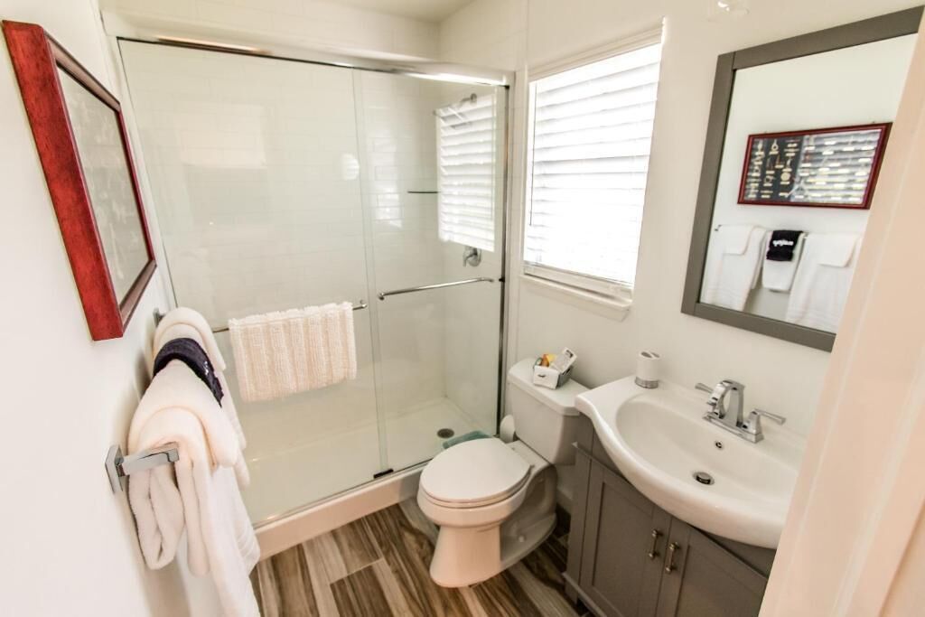 Une salle de bain avec une douche à parois de verre, des toilettes, un lavabo et un miroir.