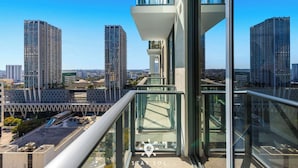 Ein Hochhaus mit Glasbalkon und Blick auf eine Stadtlandschaft.