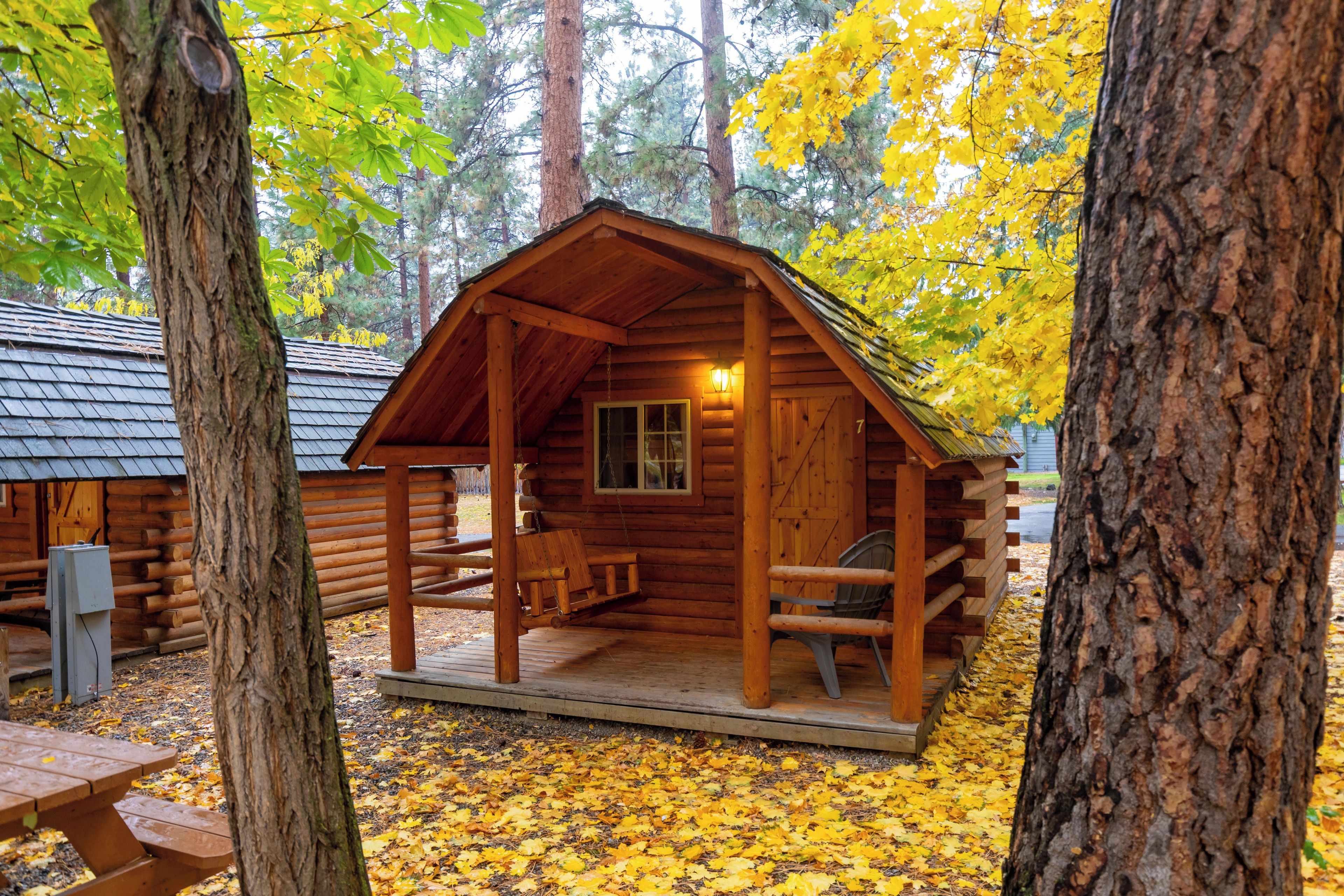 A wooden cabin with a porch, a bench, and a table.