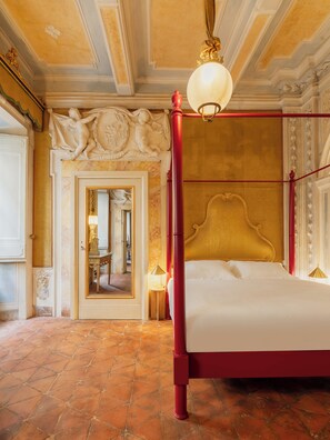A four-poster bed with a gold headboard, a red metal frame, and a white bedspread. - Guelfa 19 - (1) - Two Bedroom Apartment, Sleeps 4 (Cortona)