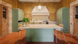 A kitchen with a marble countertop, green cabinets, and a central island with stools. - Guelfa 19 - (1) - Two Bedroom Apartment, Sleeps 4 (Cortona)