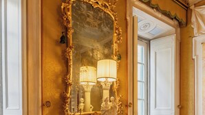 A room with a large ornate mirror, a table with a lamp, and a door leading to another room. - Guelfa 19 - (1) - Two Bedroom Apartment, Sleeps 4 (Cortona)