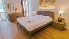 A bedroom with a bed, bedside table, dresser, mirror, and artwork on the wall. - La Piazzuola - One Bedroom Apartment, Sleeps 4 (Salo)