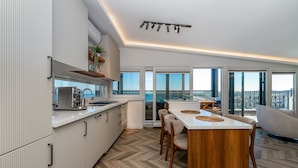 A modern kitchen with a herringbone floor, a dining area with a wooden table, and large windows offering a view.