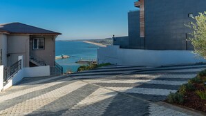 A coastal building with a staircase leading to a terrace overlooking the sea.
